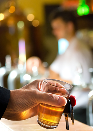 man holding car key and glass in the barの写真素材