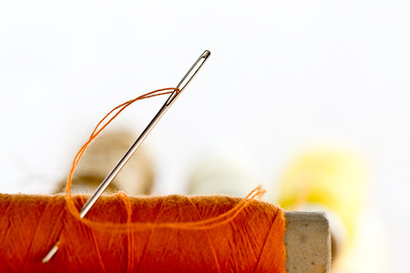 needles and orange color thread on the white backgroundの写真素材