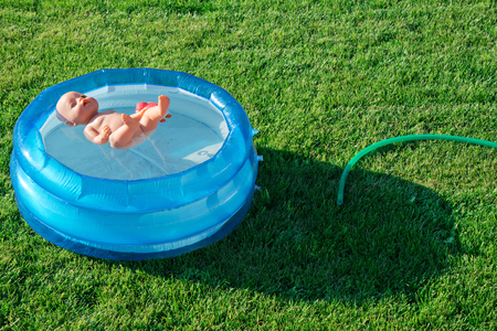 a small doll floating in the plastic poolの写真素材