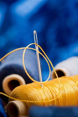 needle and yellow thread on the blue backgroundの写真素材