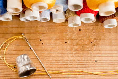 needle with thread and thimble o the wooden desk