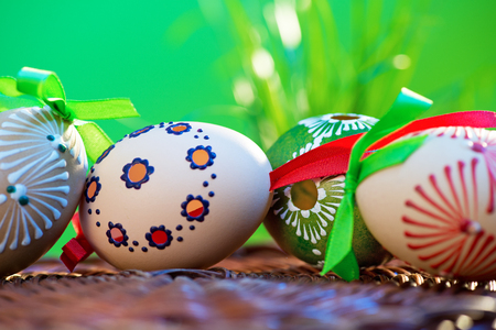 Painted easter eggs in the wicker basket in the grass.の写真素材