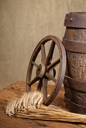 Still life with old wooden barrel,wheel and barleyの写真素材