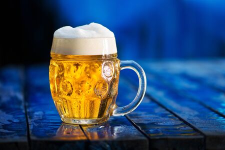 Glass of beer on the blue wooden background.の写真素材
