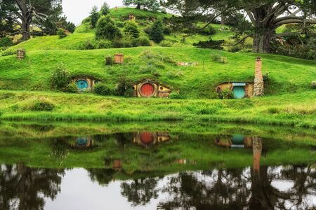 hobbit holes in hobbiton movie set reflecting in a small lake. Taken in New Zealand.のeditorial素材