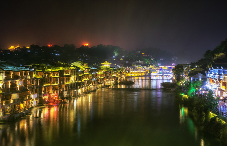 fenghuang, phoenix ancient town, night view with reflections of the town on the riverの写真素材