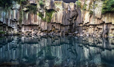 cheonjeyeon pond reflections of the cliffside and rock formations. Jeju Island, South Koreaの写真素材