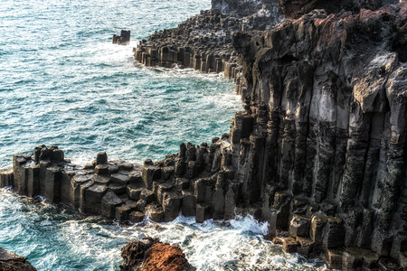 waves hitting the side of daepo jusangjeolli cliff stone pillars in jejudo, south koreaの写真素材