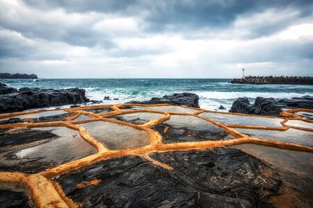 gueomri stone salt farm view with the view of the coastline in jeju island, south korea.の写真素材