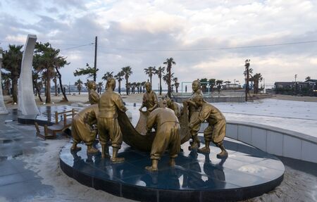 bronze statues of fishermen pulling fishing net in hamdeok seobong beach in jeju island, south koreaの写真素材