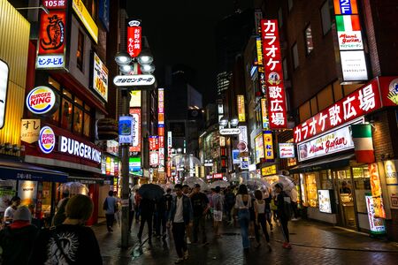 busy crowded shibuya street with various shop signs and logos lit up at night. Taken in Tokyo, Japan on June 29th 2019のeditorial素材