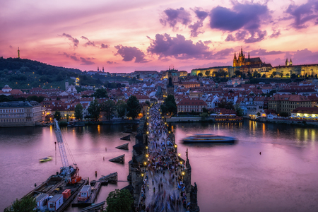 sunset over the Charles bridge and prague castle all illumiated with pink sky reflecting on the vltava river below viewed from the old town tower observatory deck.のeditorial素材