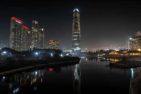 Songdo central park taken at night during autumn season with the view of the iconic hotel in the...