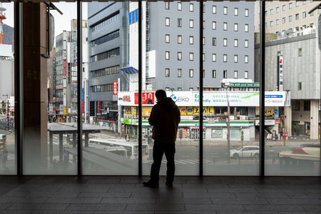 Silhouette of a man standing in front of an open view window with a view of Nagano downtown. Taken in Nagano Station, Japan. Taken on January 22 2023のeditorial素材