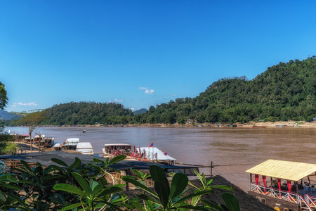 The view of Mekong River in Luang Prabang with small boats and houses nearby. Taken in Luang Prabang, Laosの写真素材