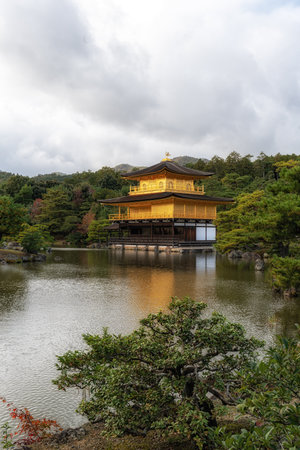 Kinkakuji golden pavilion on a small pond taken during autumn foliage season during a small rain. Famous landmark temple in Kyoto, Japanの写真素材