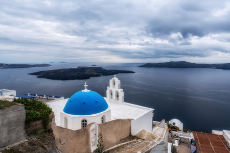 Three bells of fira in Santorini Greece taken during a rain storm clouds. Famous landmark in Santorini, Greeceの写真素材