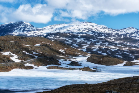 Scenic Route Sognefjellet surrounded by snow capped mountains and frozen lake. Taken in Norway