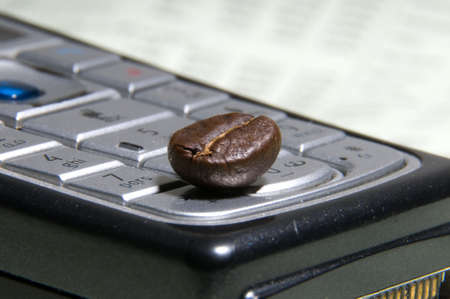 Business coffee. Coffee bean lying on a mobile phone.の写真素材