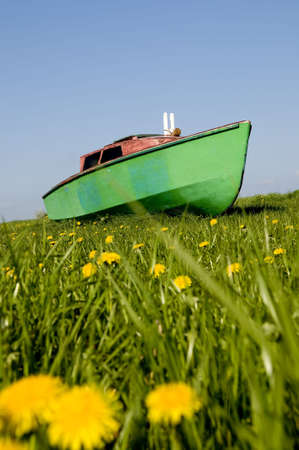 Green boat sailing over spring meadowの写真素材