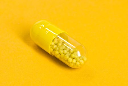yellow capsule on yellow backgroundの写真素材