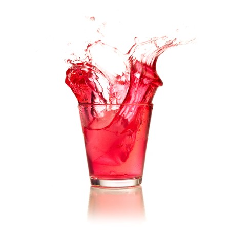 Red cocktail splashing on a glass on white backgroundの写真素材