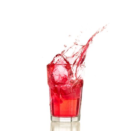 Red cocktail splashing on a glass on white backgroundの写真素材