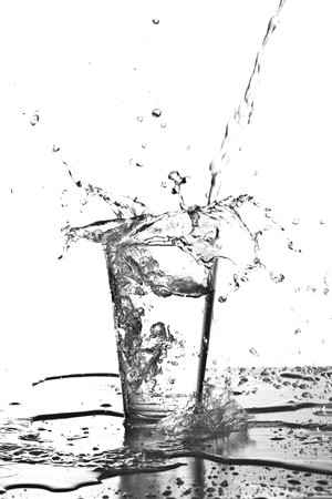 water splashing into a glass on white backgroundの写真素材
