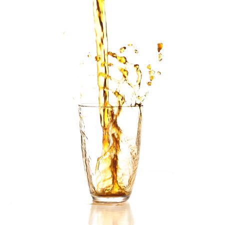 beverage splashing into glass on a white backgroundの写真素材