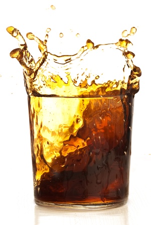 beverage splashing into glass on a white backgroundの写真素材