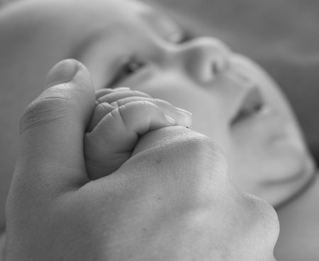 adult hand holding a baby hand closeup, black and whiteの写真素材