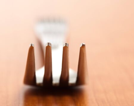 metal fork on a wooden surface, extreme closeupの写真素材