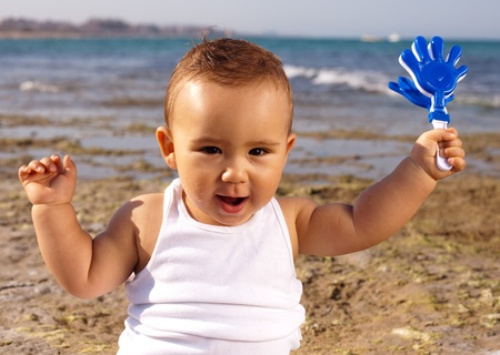 baby playing with a toy with th sea as a backgroundの写真素材