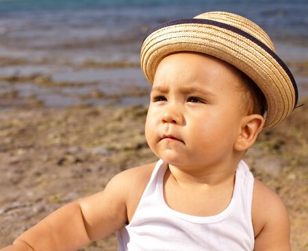baby with a straw hat in the beach