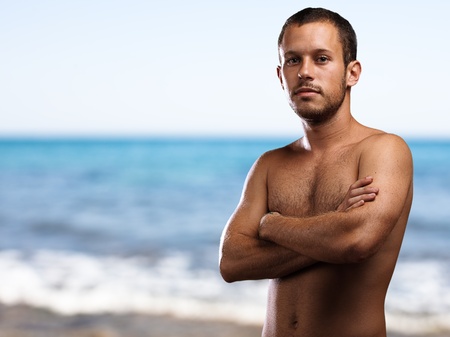 man shirtless with arms crossed in the beachの写真素材
