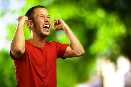 man happy shoutting against a nature backgroundの写真素材