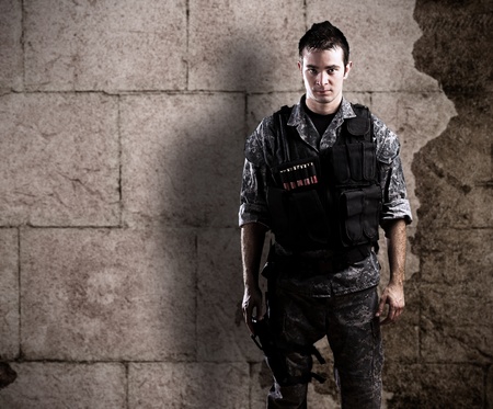 young armed soldier against a grunge background
