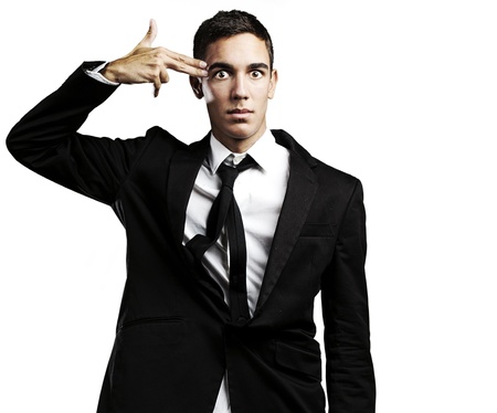 portrait of young man doing suicide symbol gesture against a black backgroundの写真素材