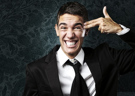 portrait of young man doing gun symbol against a grunge wallの写真素材