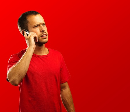 young businessman calling on mobile phone on red backgroundの写真素材