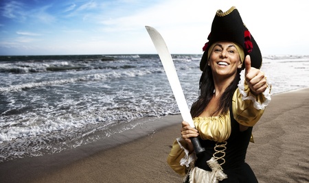 portrait of pirate woman holding a sword and gesturing ok at the beachの写真素材