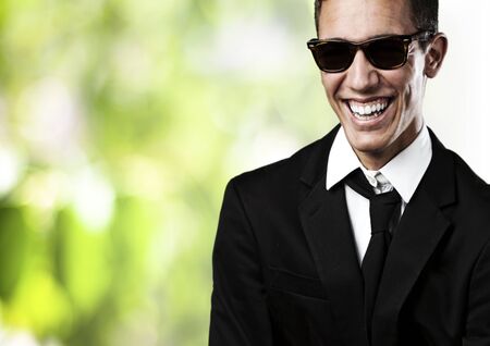 portrait of young business man with suit and sunglasses  against plants backgroundの写真素材