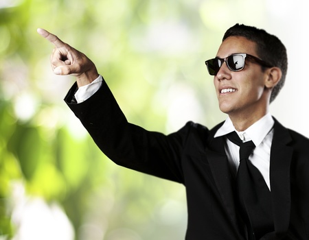 portrait of young business man pointing up against a nature background の写真素材