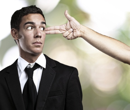 man gesturing gun pointing a business man against a nature backgroundの写真素材