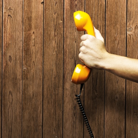 orange vintage telephone against a wooden wallの写真素材