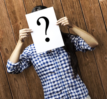 portrait of young woman holding interrogation symbol against a wooden wallの写真素材