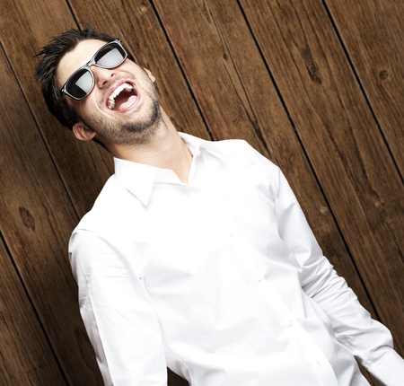 portrait of young man smiling wearing sunglasses against a wooden wallの写真素材
