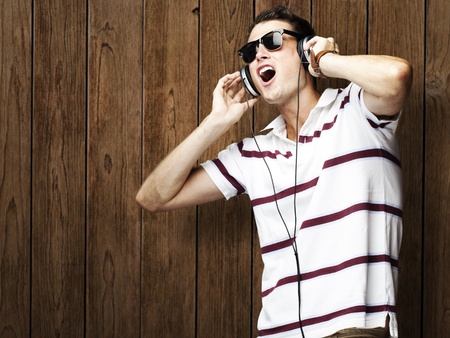 portrait of young man listening to music against a wooden wallの写真素材