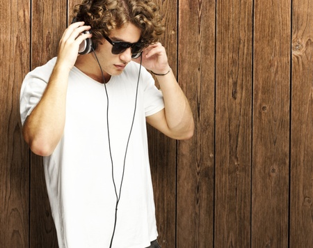 portrait of young man listening to music against a wooden wallの写真素材
