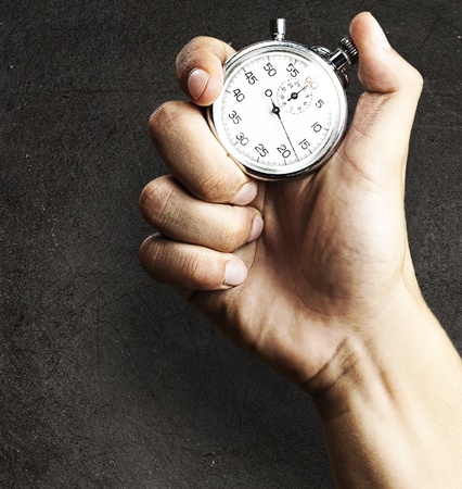 hand holding stopwatch against a grunge background
